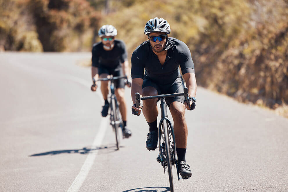 Two cyclists training outdoors, focusing on building a strong base of aerobic fitness