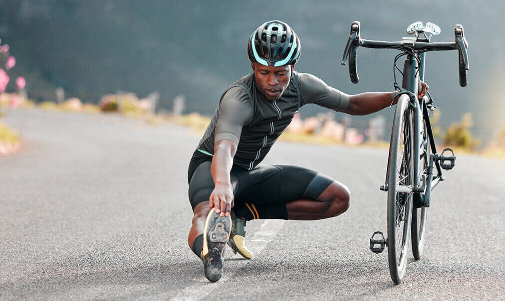 A cyclist stretching beside his bike